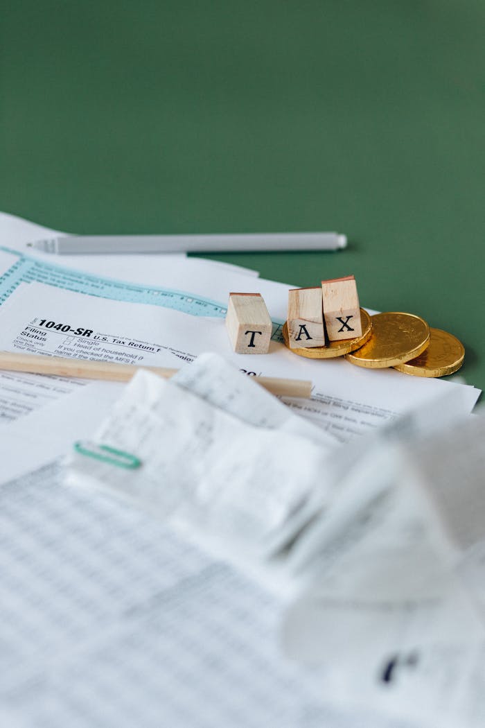services-03 Tax forms, coins, and block letters spelling TAX on a green background, symbolizing finance.