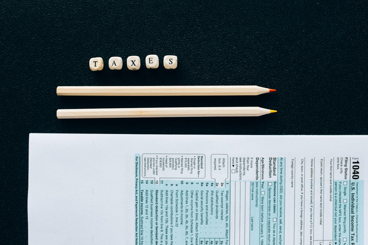 why-choose-us Flat lay of 1040 tax form with pencils and TAXES blocks on black background.