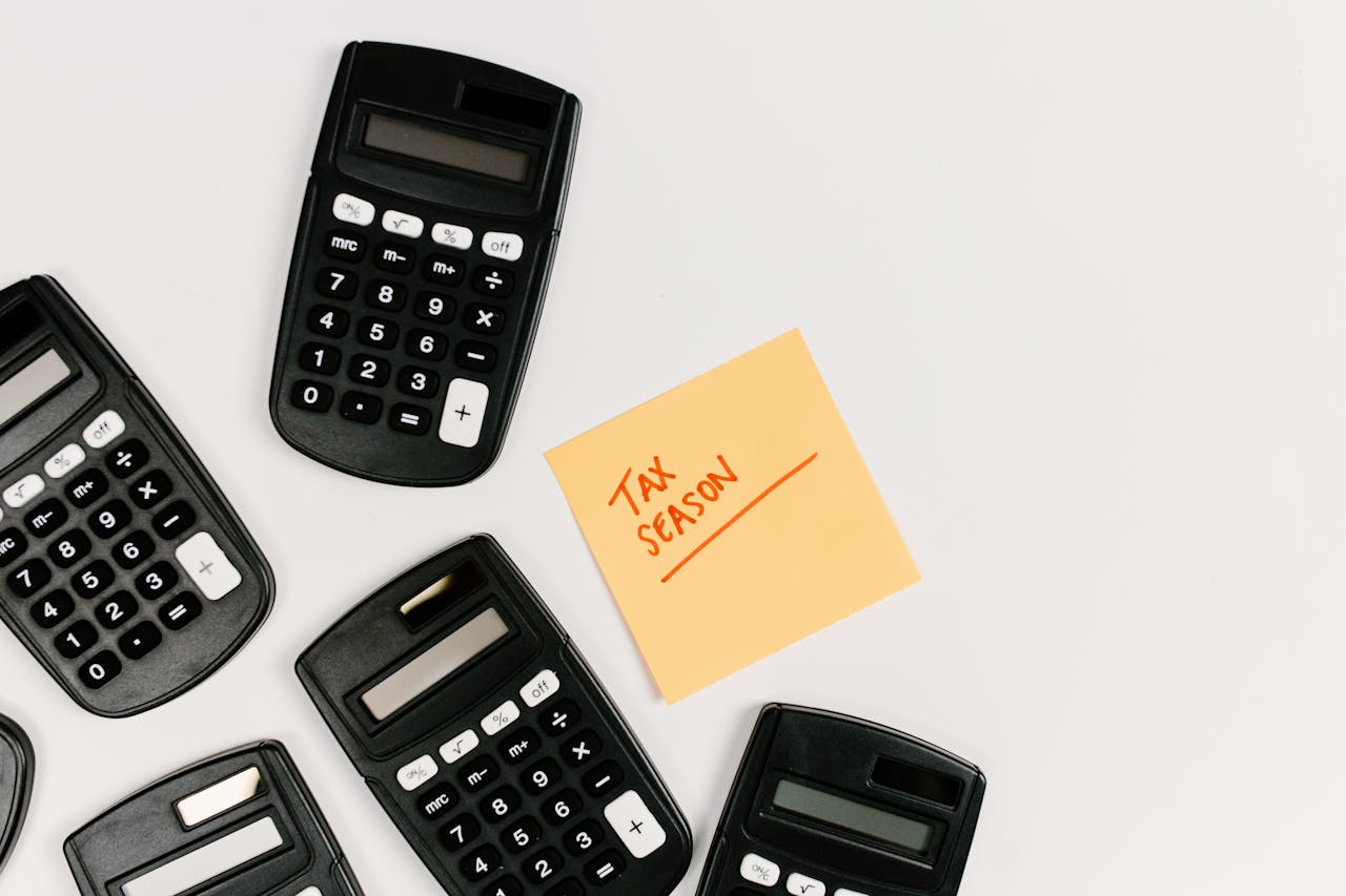 hero-img-02 Top view of calculators with a tax season sticky note on a white background.